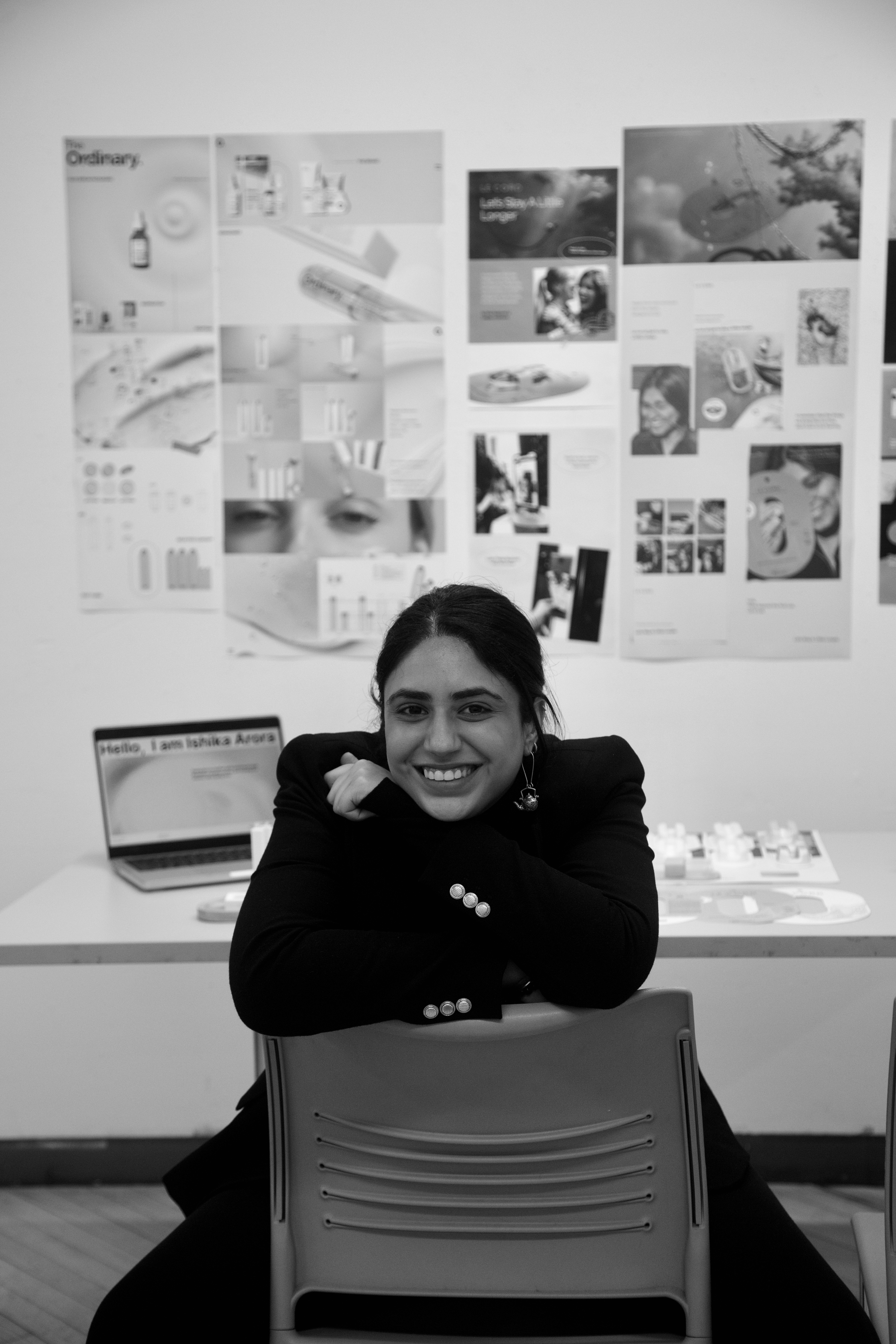 A model wearing an elegant cream blazer sits on a chair against a bright blue background, showcasing a modern and minimalist professional style.