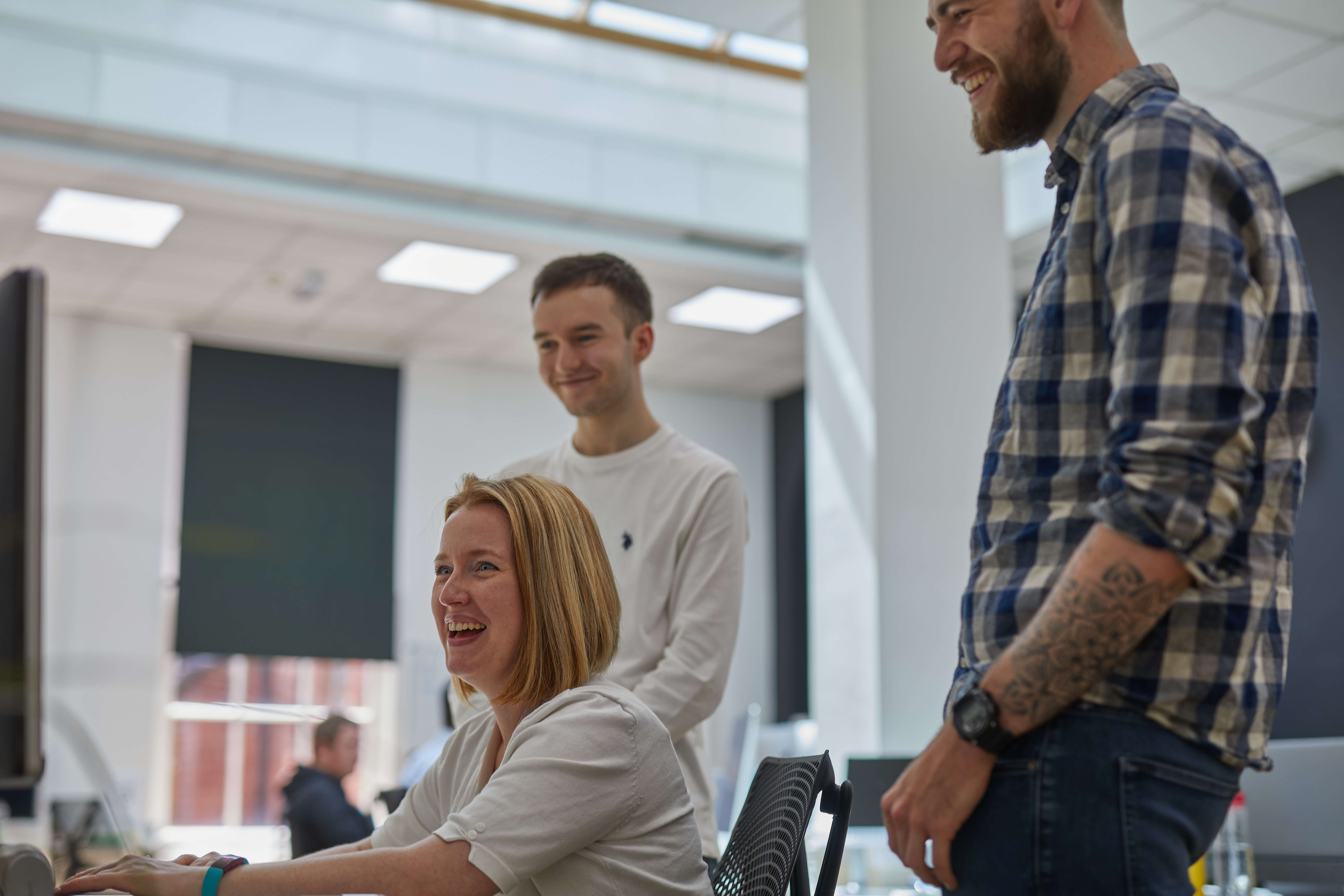 Sarah and two other software engineers smiling while looking at a monitor in the Komodo studio