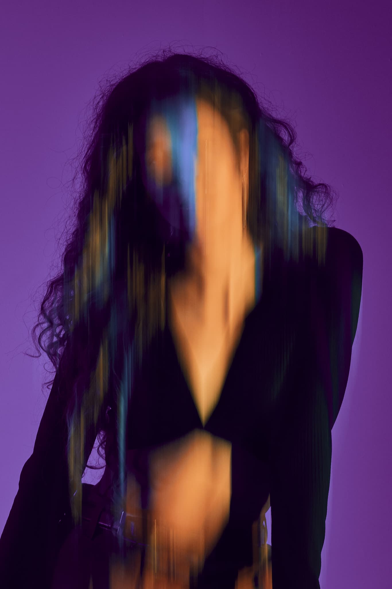 A blurred portrait of a model in motion with blue and purple lighting, taken in a Shreveport photography studio.