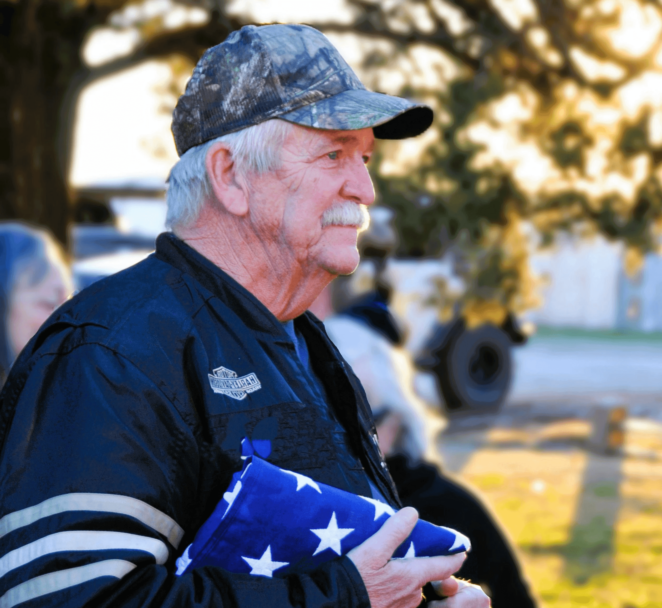 A man in a black jacket holding an american flag