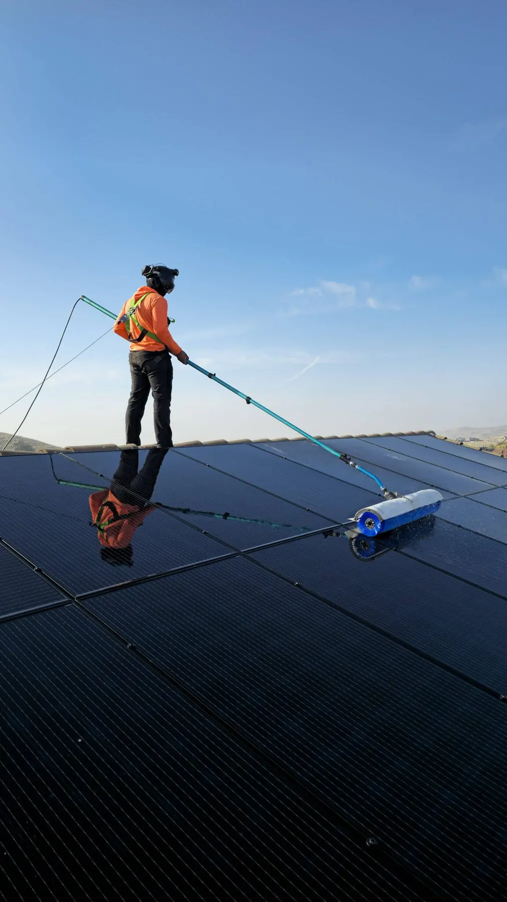 Technician cleaning a residential rooftop array with a water-fed pole | Premier Solar Service, serving Tracy, CA