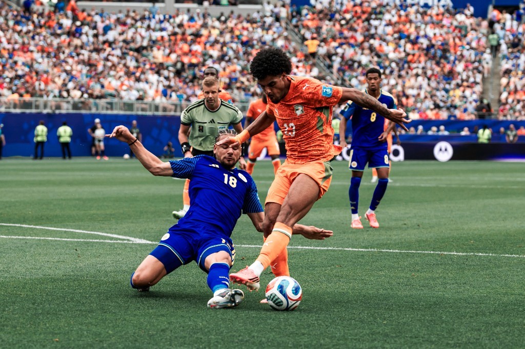 Ivory Coast's number 22 shields the ball as a Curaçao player slides in during their Group E match in Philadelphia