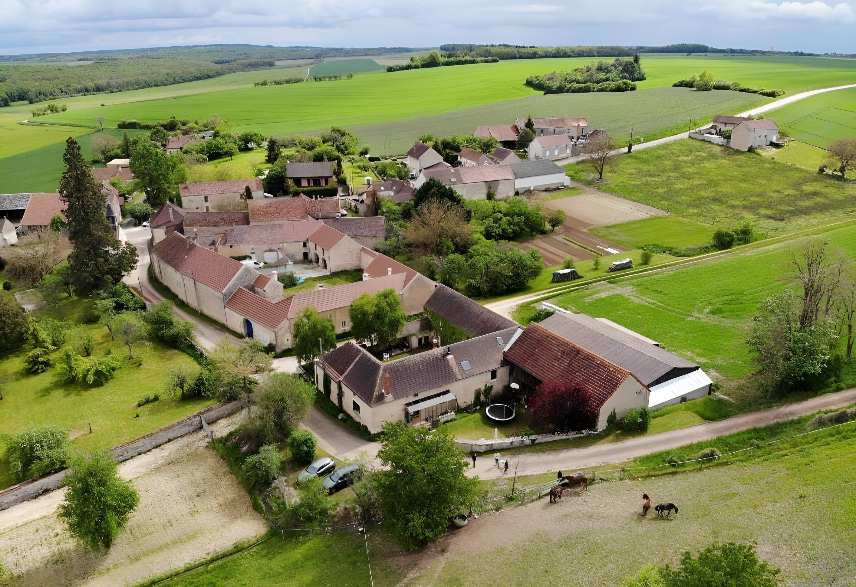 Vue aérienne d'un village rural entouré de champs verts.