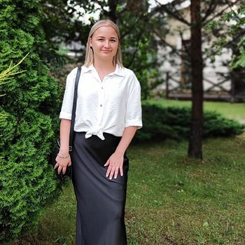 Black-and-white portrait of a man with an afro in motion, wearing a hoop earring and chain necklace, against a light gray background.