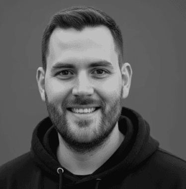 A woman with a red bow headband and bright orange and blue clothing poses against a teal and orange geometric background. Her expression is confident.