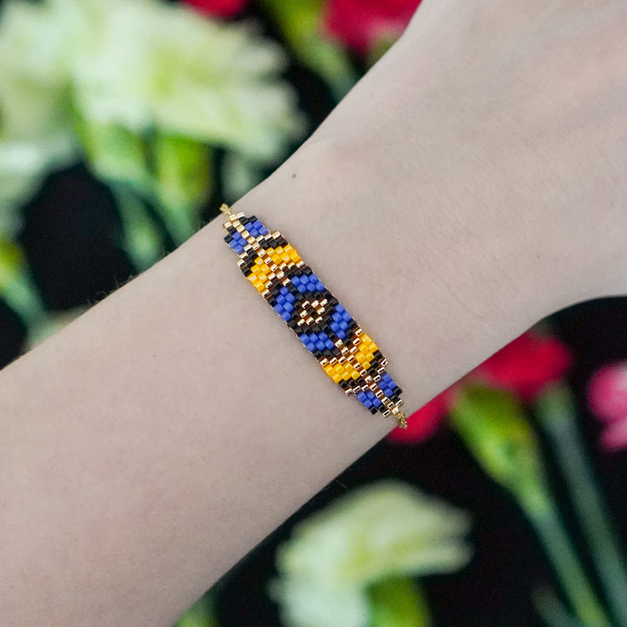 Kontrastowa bransoletka fiołkowo-żółta na nadgarstku, prezentująca geometryczny wzór i blask połyskujących koralików