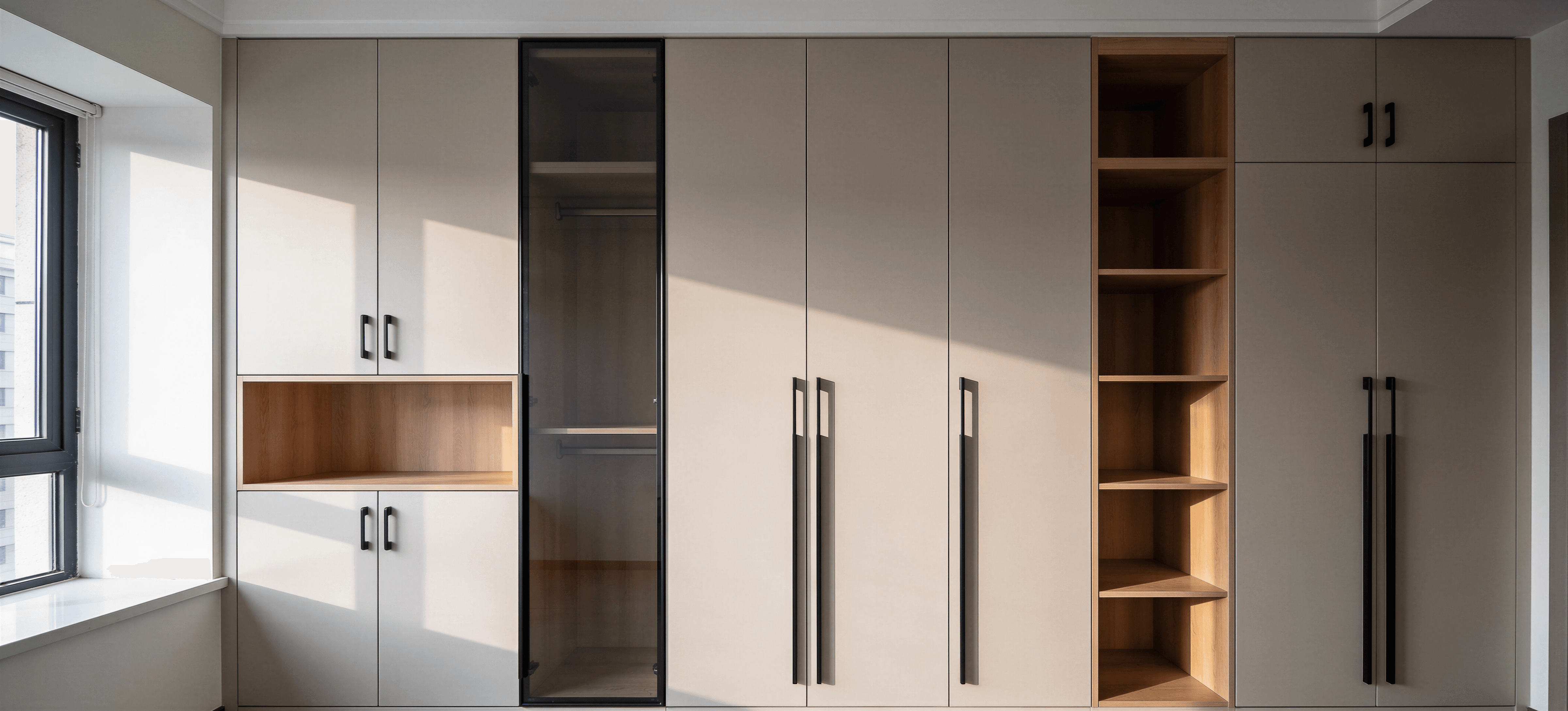 Dulap înalt alb cu panou vitrină fumuriu și nișă din lemn, compartimentare variată.