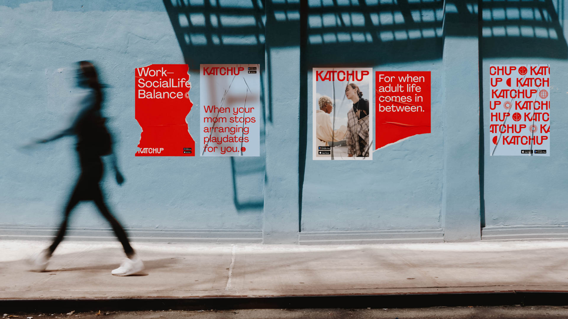 A person in motion walks past a light blue wall adorned with several posters. The posters feature red and white text and images, including phrases like “Work-Social-Life Balance,” “When your mom stops rearranging playdates for you,” and “For when adult life comes in between.” The person walking is blurred due to motion, emphasizing the posters’ prominence. The posters are affixed to the wall with visible screws or fasteners. The ground in front of the wall is a light gray concrete or paved surface.