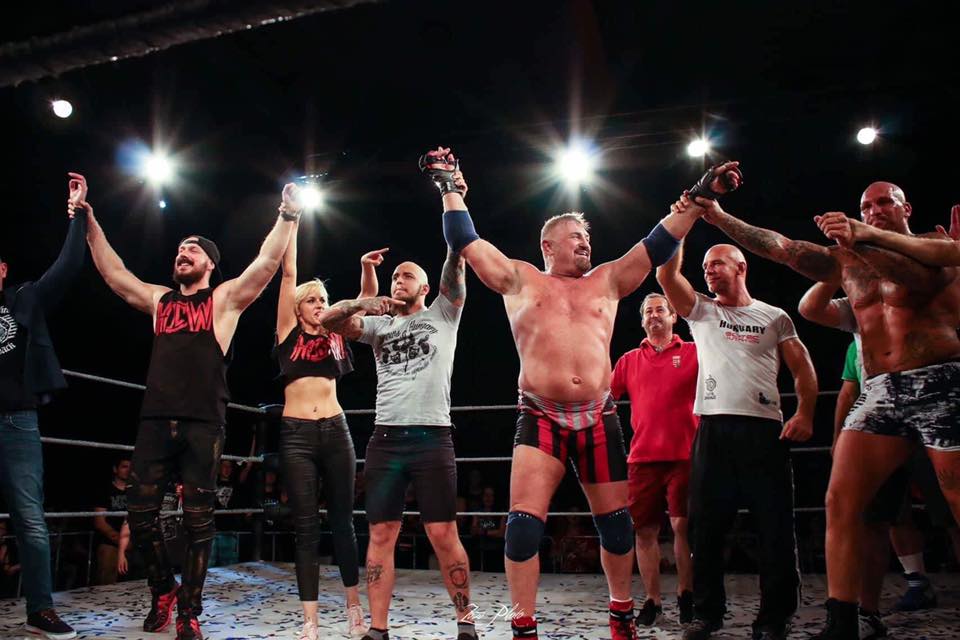 A rustic kitchen scene featuring glass jars of sourdough starter on a wooden table, with a notebook filled with handwritten recipes, a brown bowl of flour, and a beige fabric apron, illuminated by soft natural light from a window.