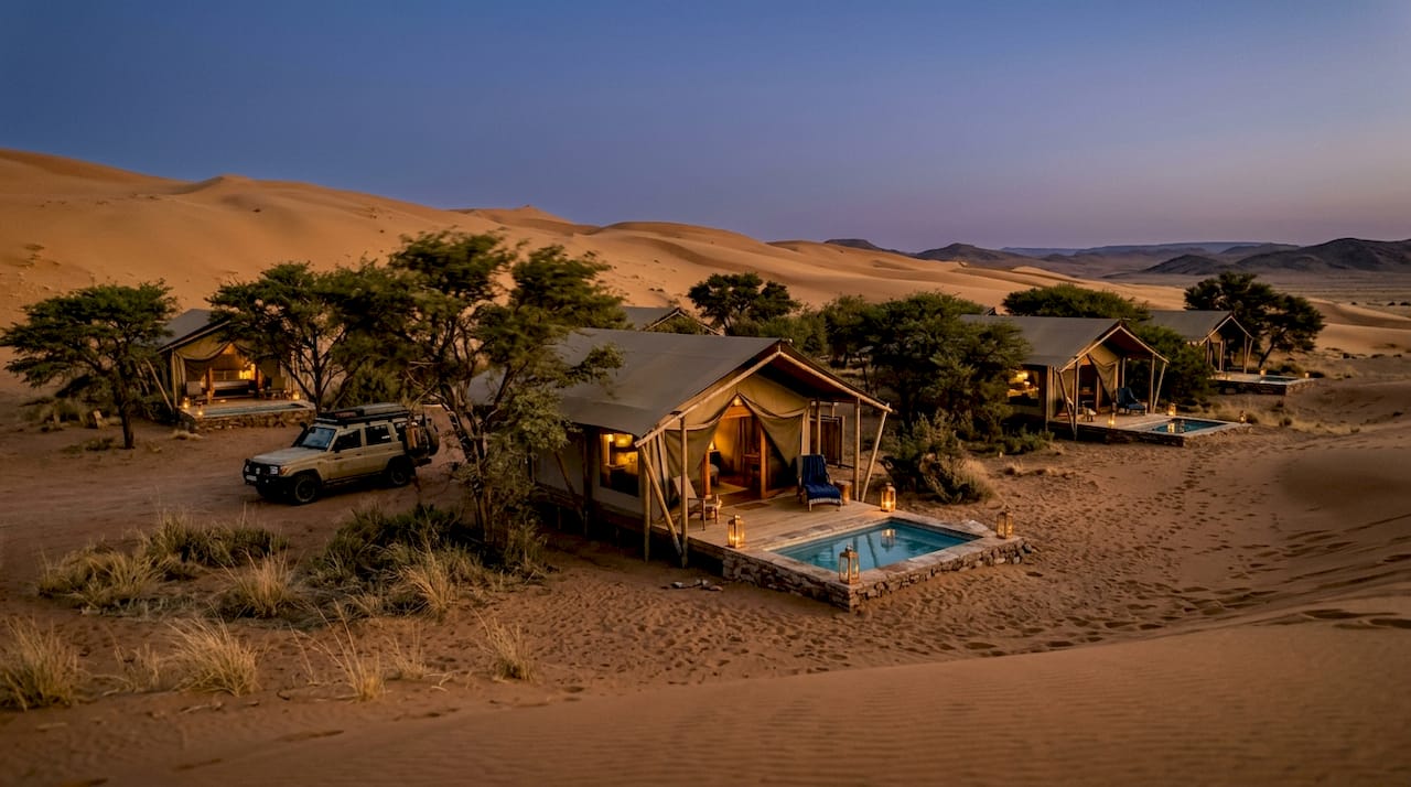 Luxury tented lodges amid Namibian desert dunes at sunset