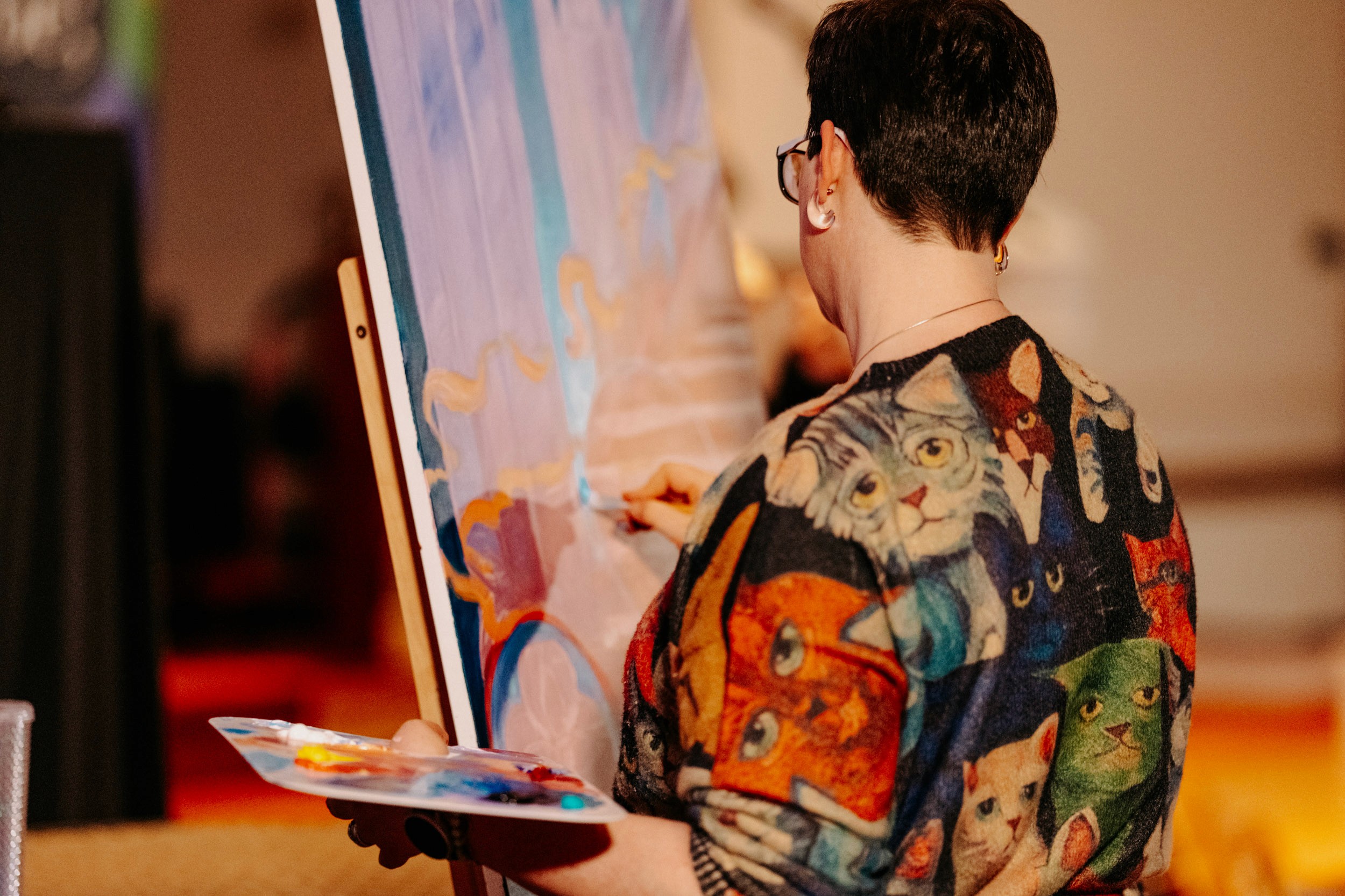 Artist painting on canvas during the Queer Open Mic (QOM) hosted by be; community in Bridgewater, Massachusetts