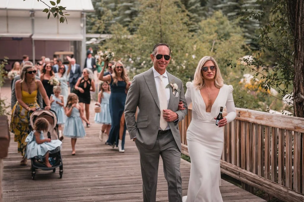 Newlyweds walking along a boardwalk with guests behind them