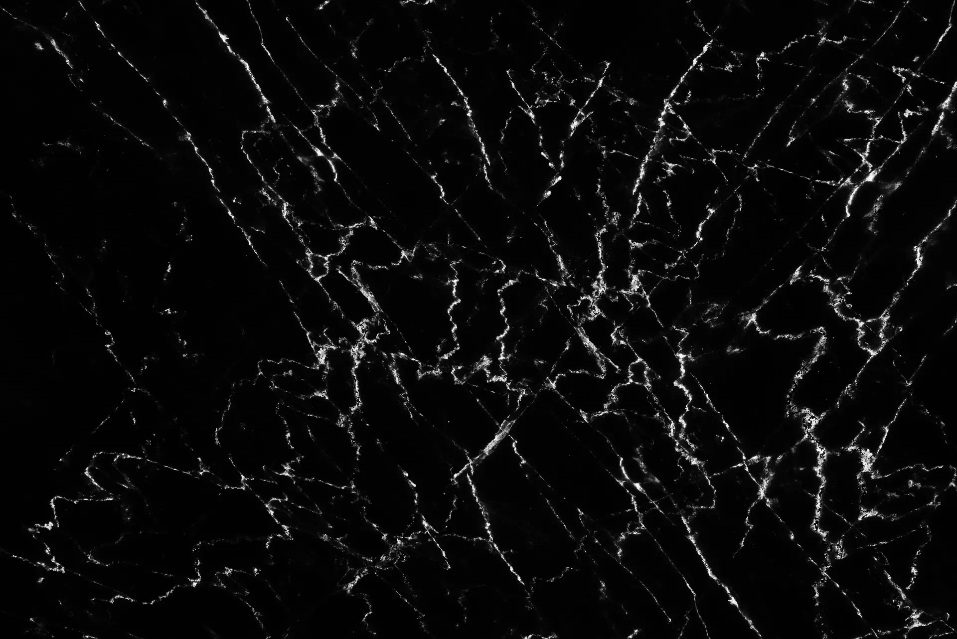 A deep black slab of Black Marquina marble with striking, high-contrast white veins.