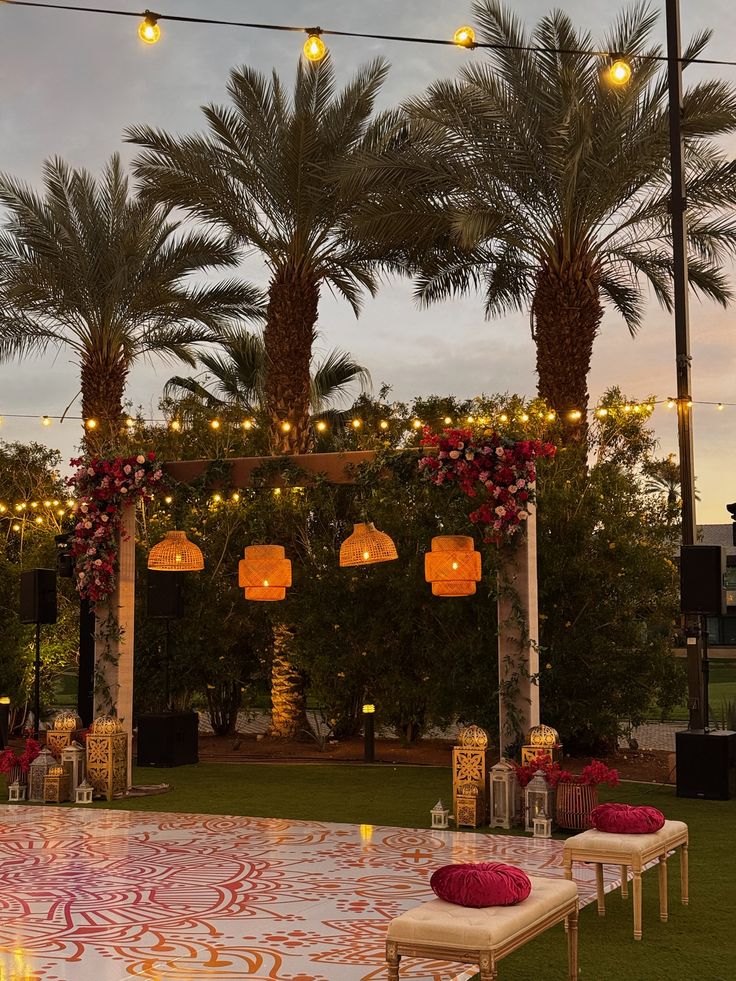 A serene outdoor wedding setup with white chairs arranged on green grass under a canopy of trees.