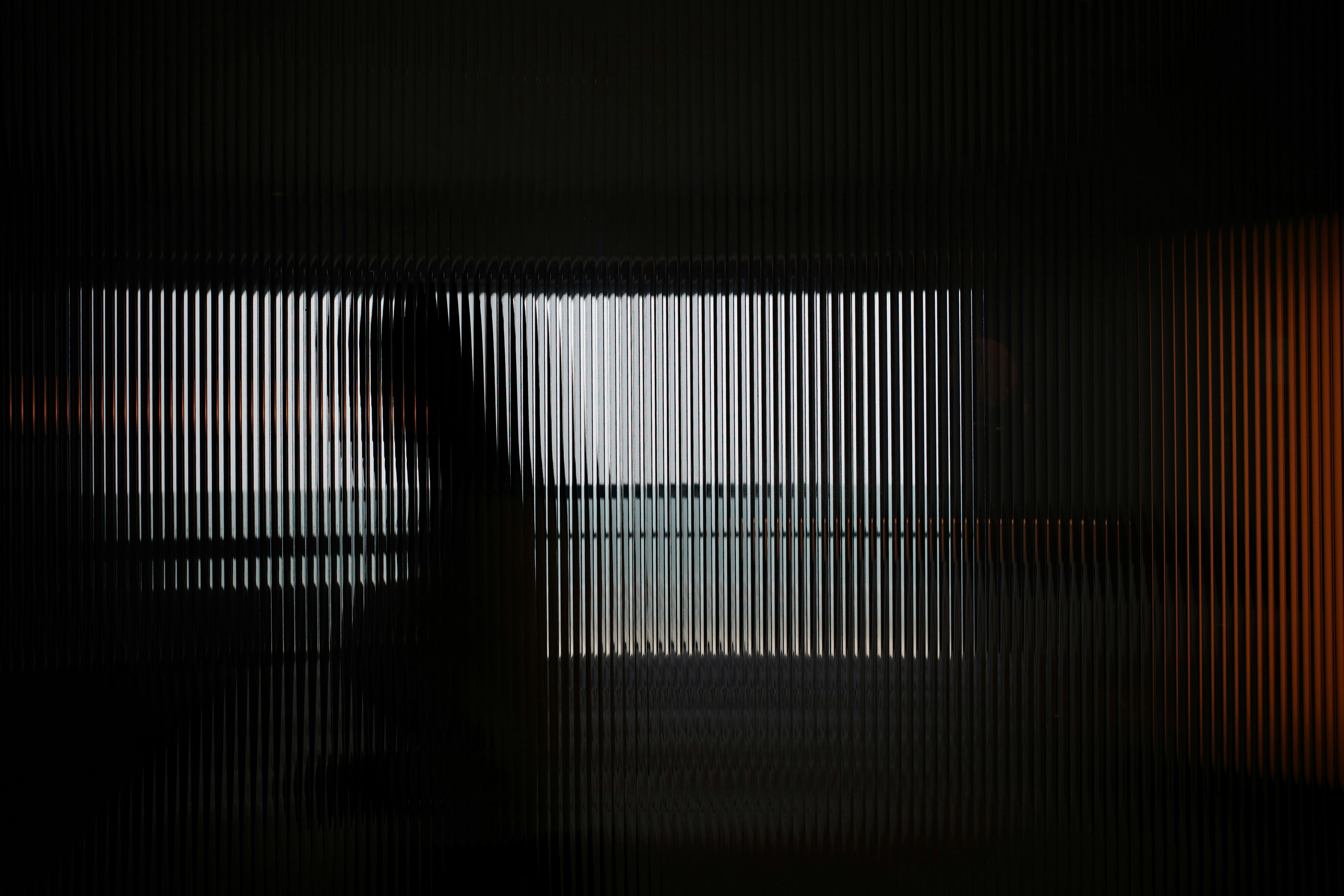 Blurred figure seen through a striped glass panel