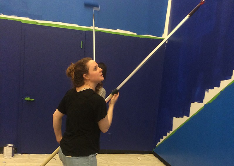 a person painting the wall in blue