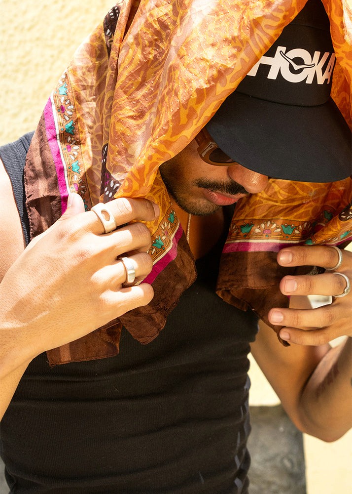 Man wearing a hoka cap, scarf and silver rings