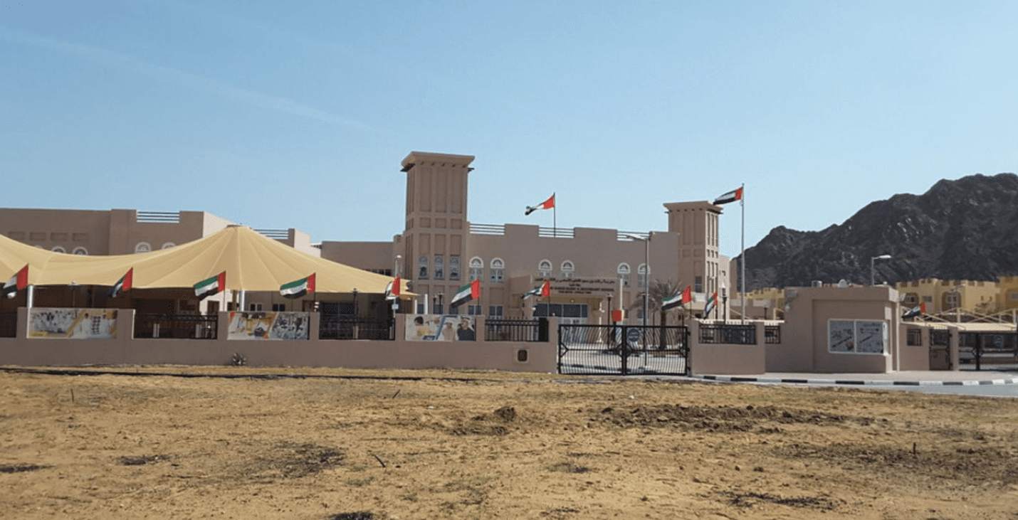 A picturesque lake surrounded by majestic mountains and a bright blue sky in Hatta.