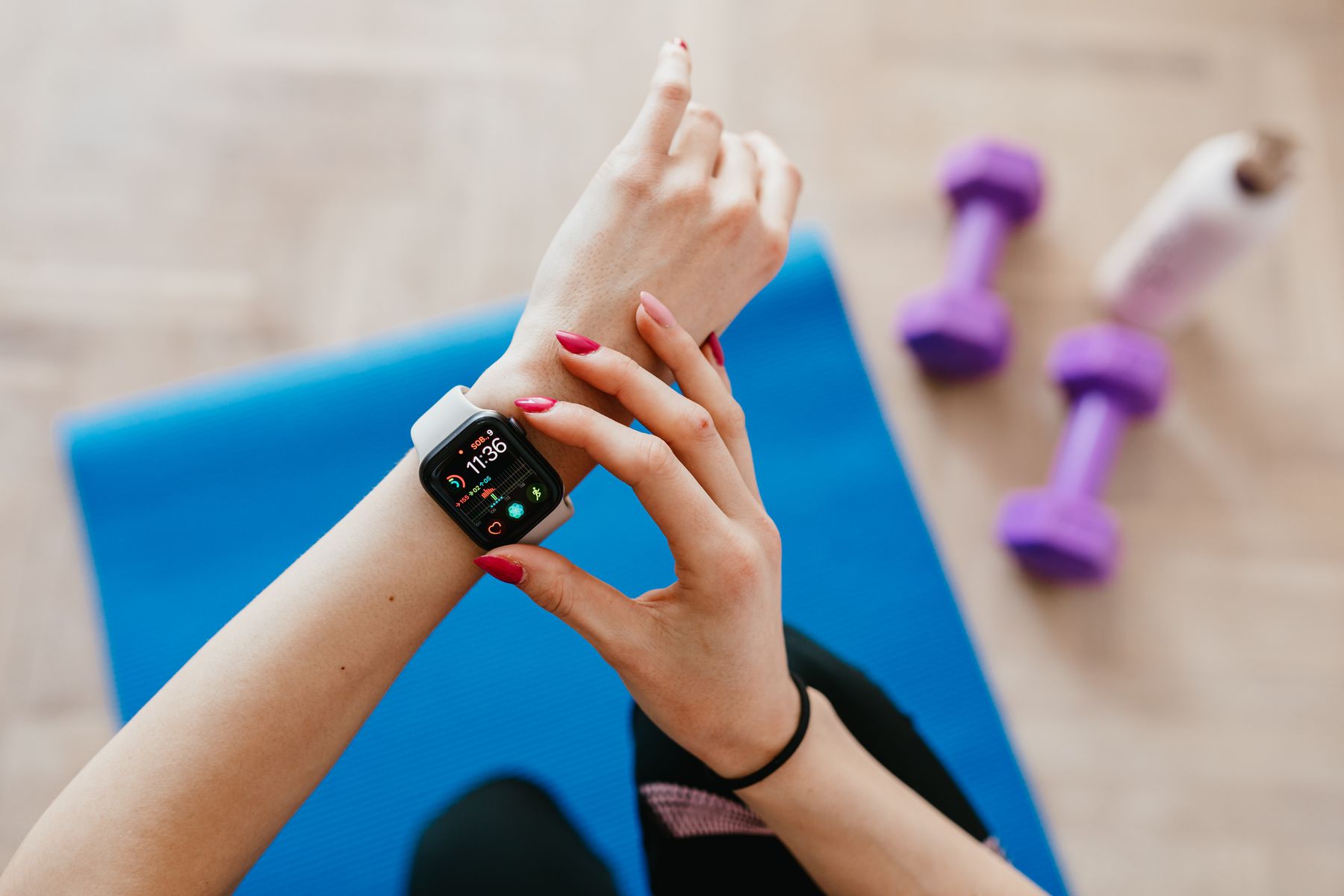 A woman checking a smartwatch beside workout equipment