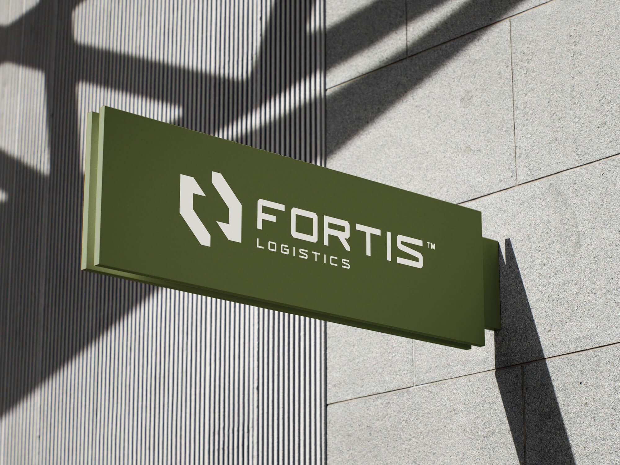 A close-up of an outdoor, rectangular hanging business sign for FORTIS LOGISTICS. The sign is a deep olive green color with the logo and text in white. The logo is an abstract, angular shape suggesting movement or arrows. The sign is mounted on a textured, light gray stone wall, and a pattern of vertical shadow lines falls across the background.
