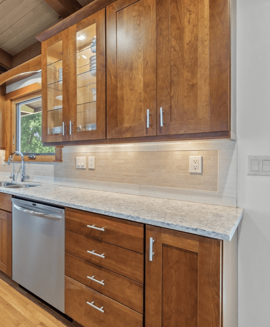 The original kitchen — walnut Kraftmaid shaker cabinets with ornate upper crown molding and a busy tile backsplash