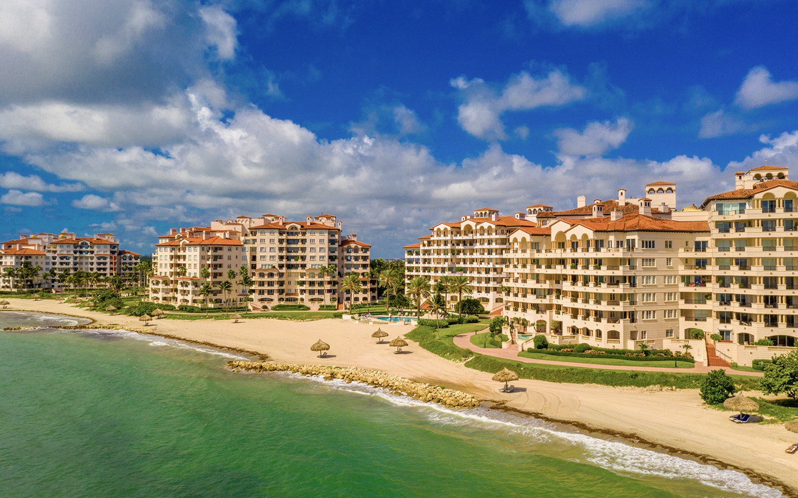 Luxury beachfront condos on Fisher Island, Miami with palm trees and ocean view.