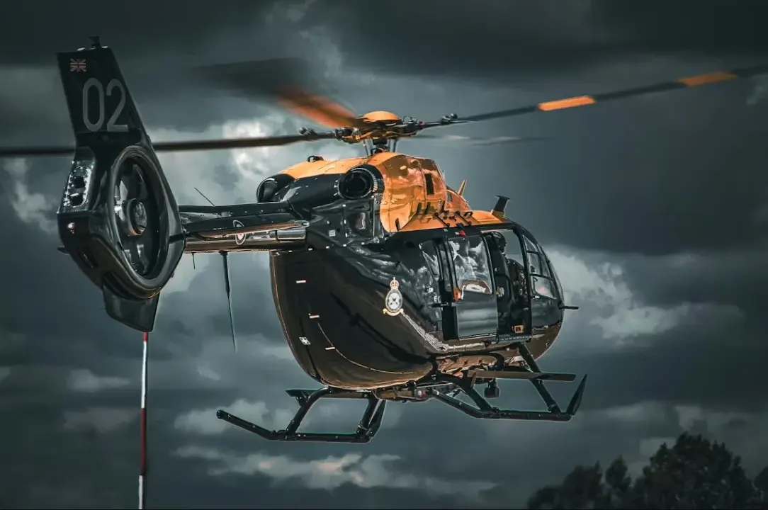 Helikopter im Flug vor Gewitterhimmel – Luftfahrtversicherung für Helikopter und Jets