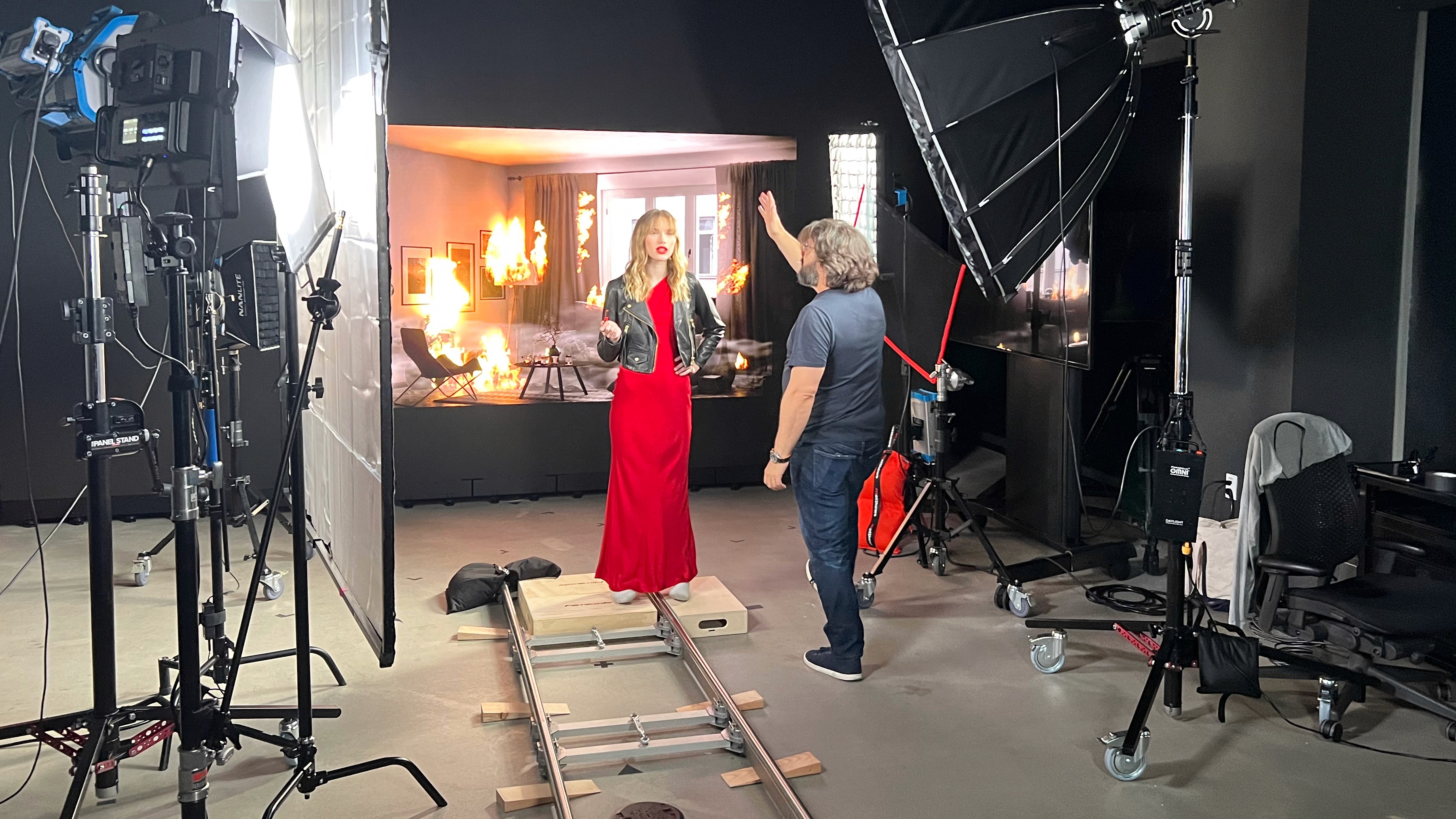 Michael Winokur directing a model in a red gown on a camera dolly track, with an LED wall showing a burning room behind her, on the set of Love Flame