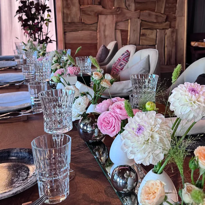 Modern dining table with floral centerpieces, black and white plates, and silver decor accents