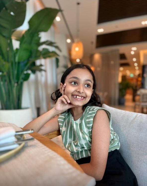 Woman in red outfit poses by a red telephone booth.
