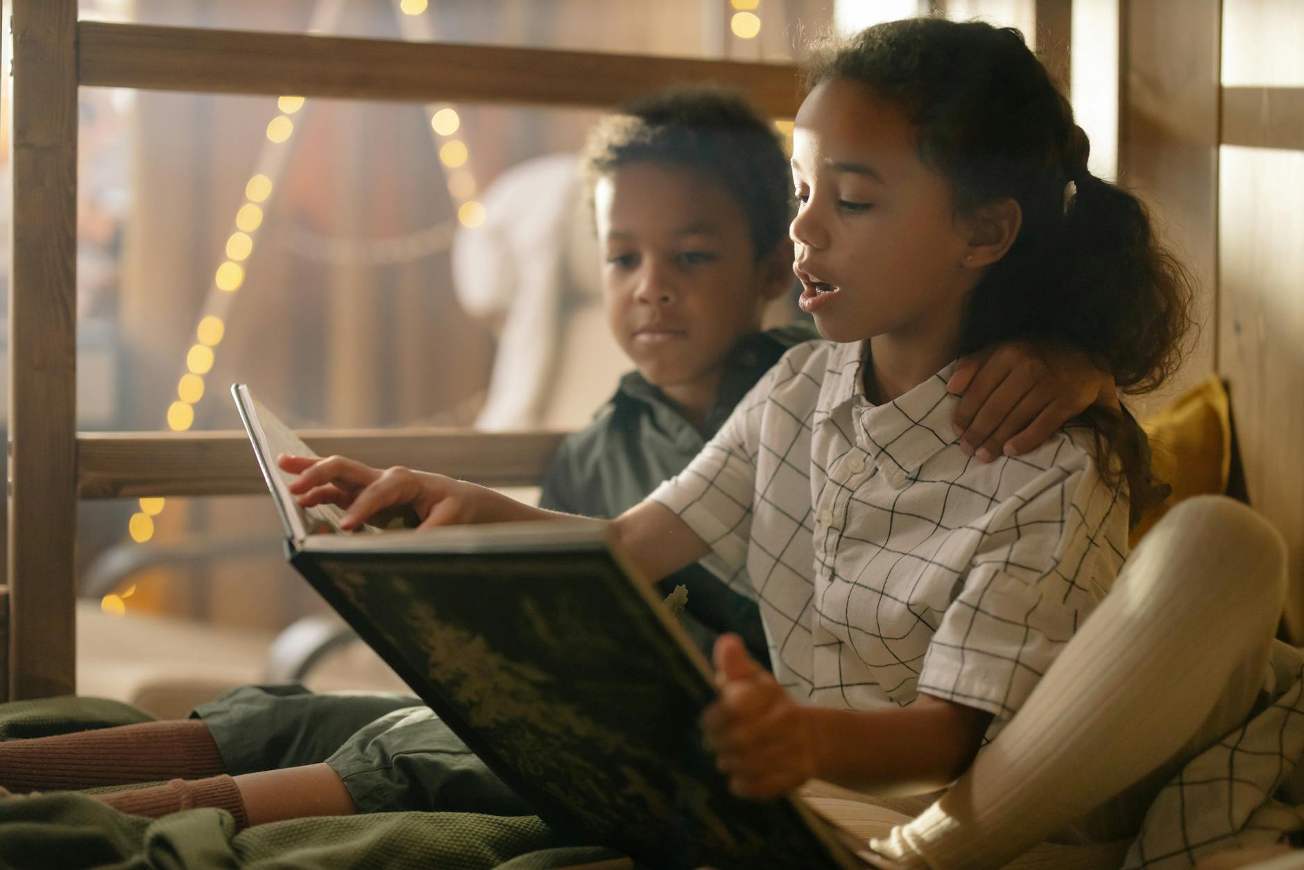 A diverse group of young children sitting together on a playground bench sharing a brightly illustrated storybook.