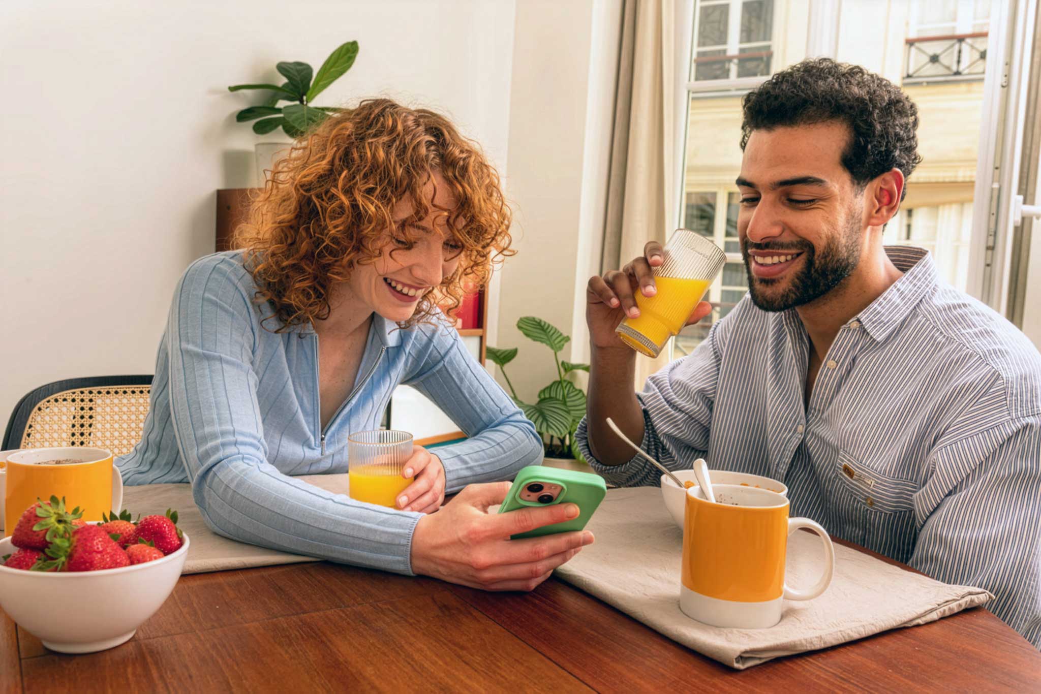 woman holding a phone and man looking at the phone. both are smiling