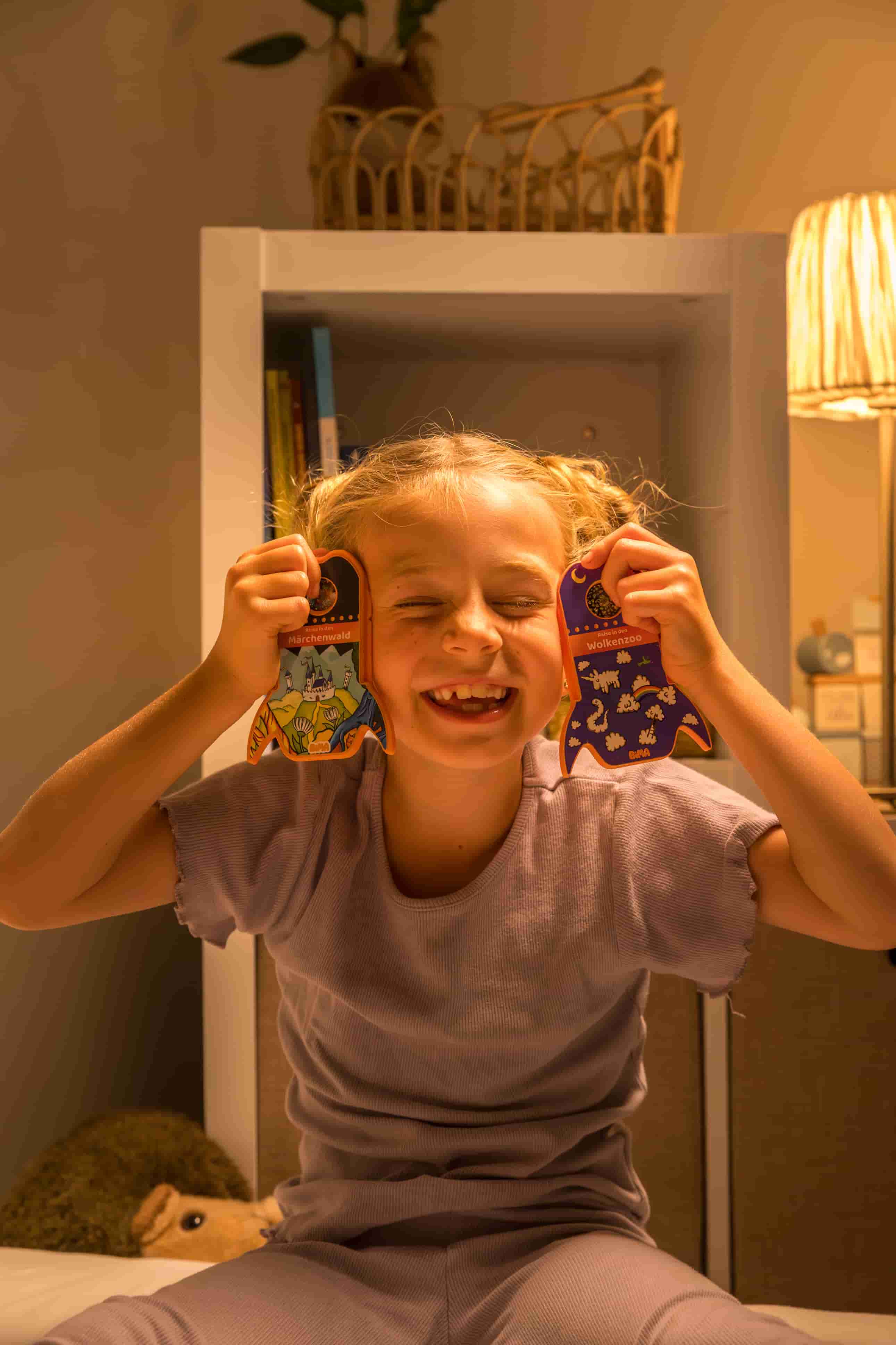 Ein Kind hält zwei BiMA Raketen neben ihren Kopf