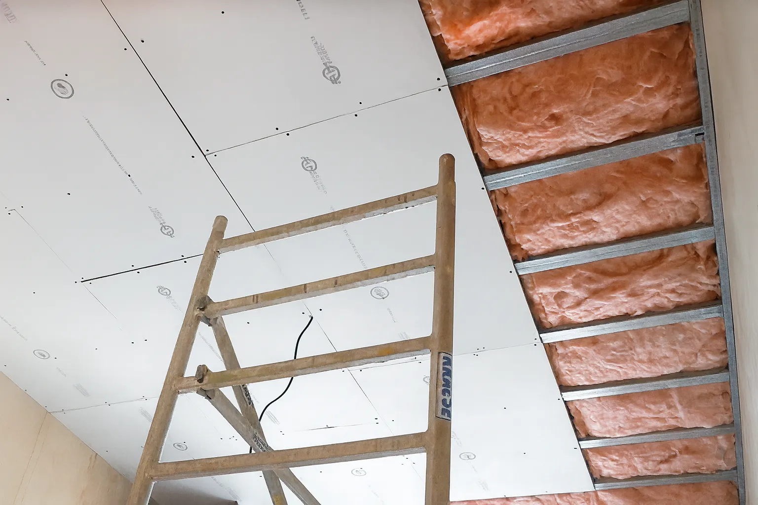 Instalace protihlukových desek na stropní konstrukci s viditelným montážním roštem a připraveným povrchem pro zvukovou izolaci