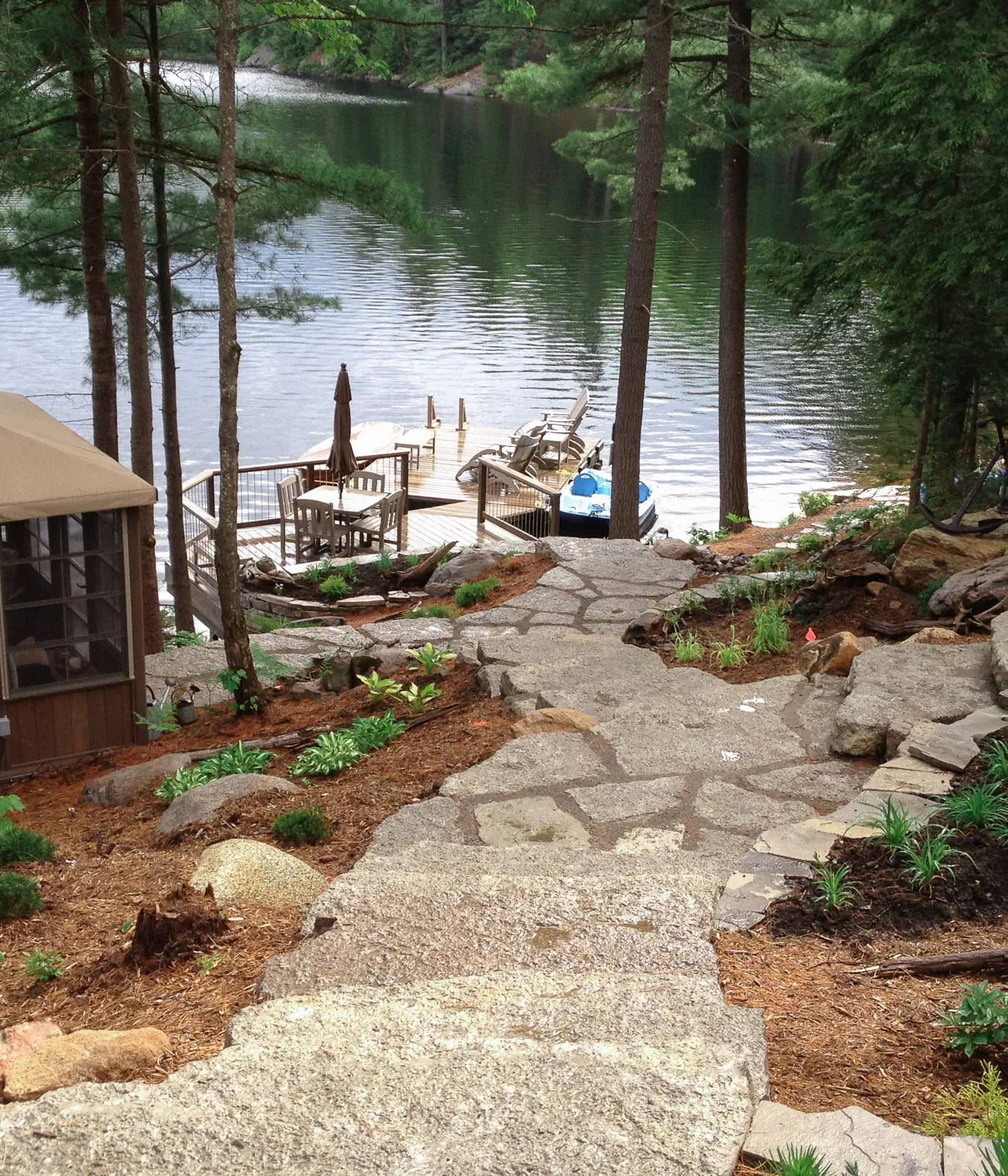 Rustic split limestone patio space with stone steps down to a dock.
