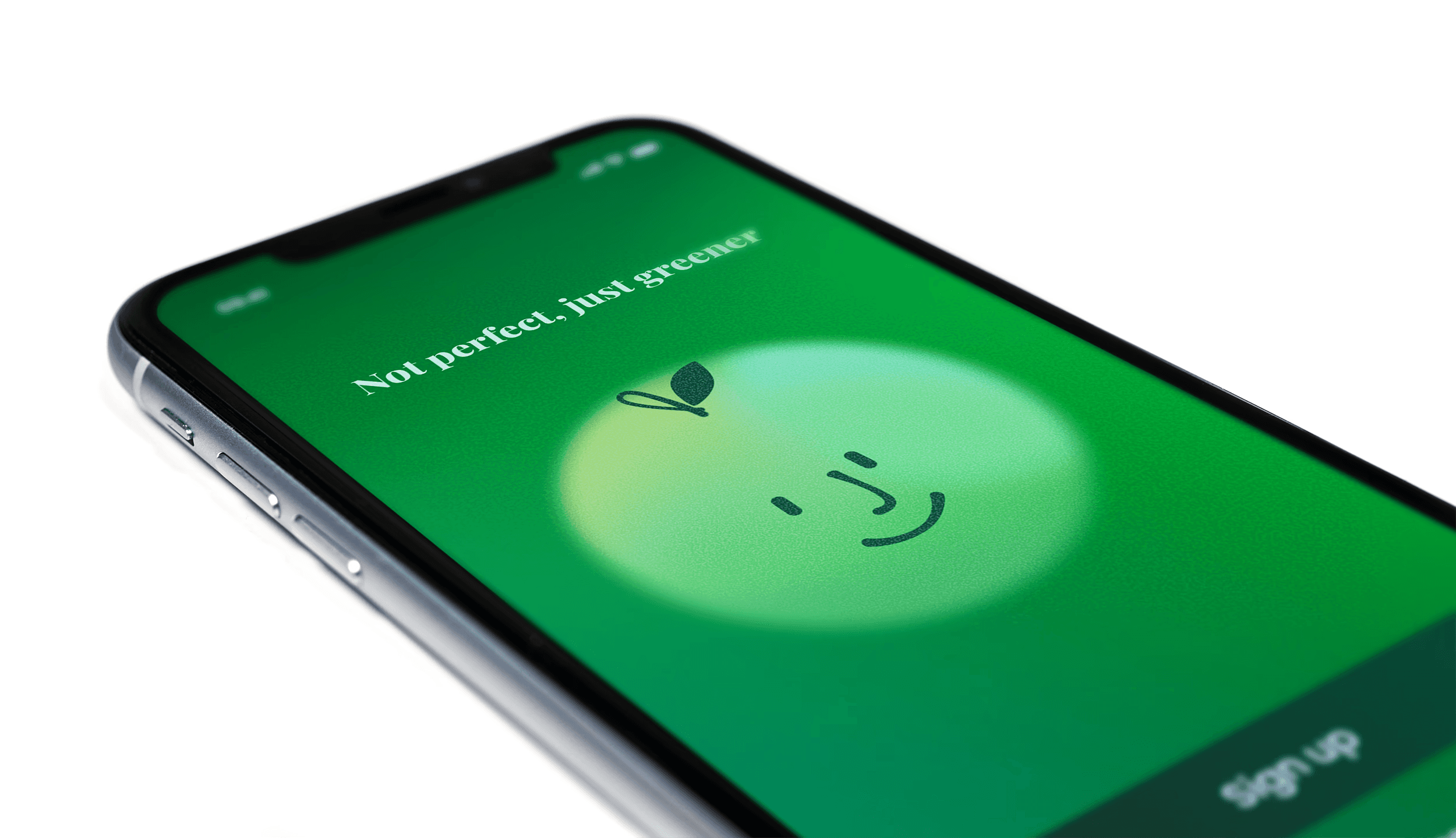 iPhone screen laying flat on a table with Greener welcome screen and the text "Not perfect, just greener"