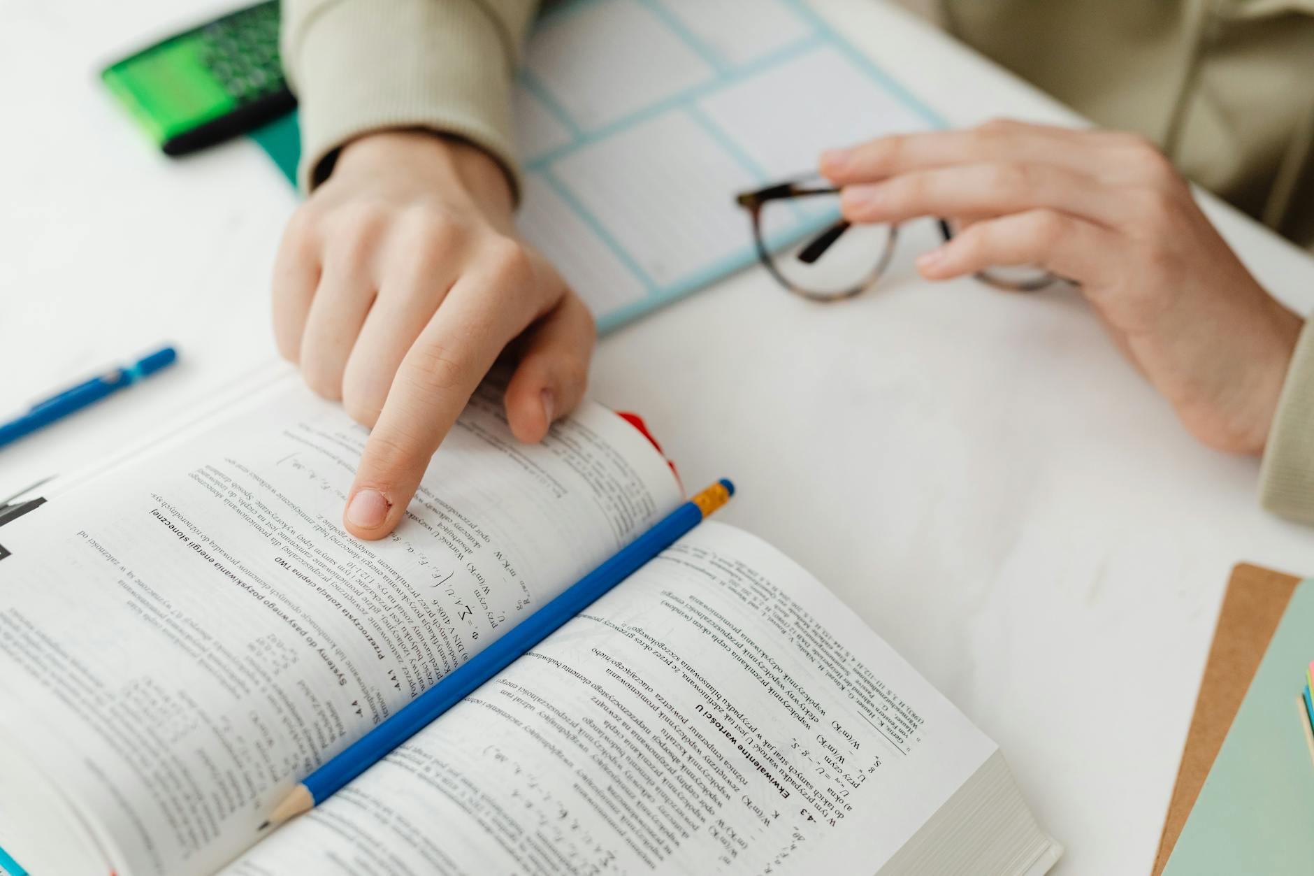 Close-up of a student writing observations in a lab notebook next to a calculator and a ruler.
