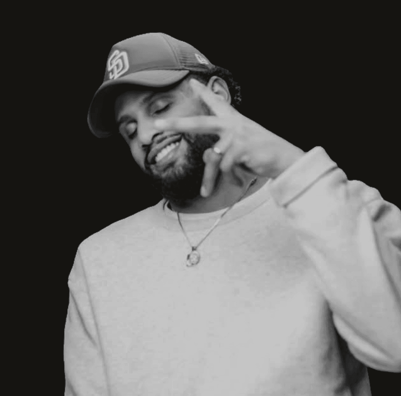 Young woman with curly hair, glasses, and an orange sweater smiling.