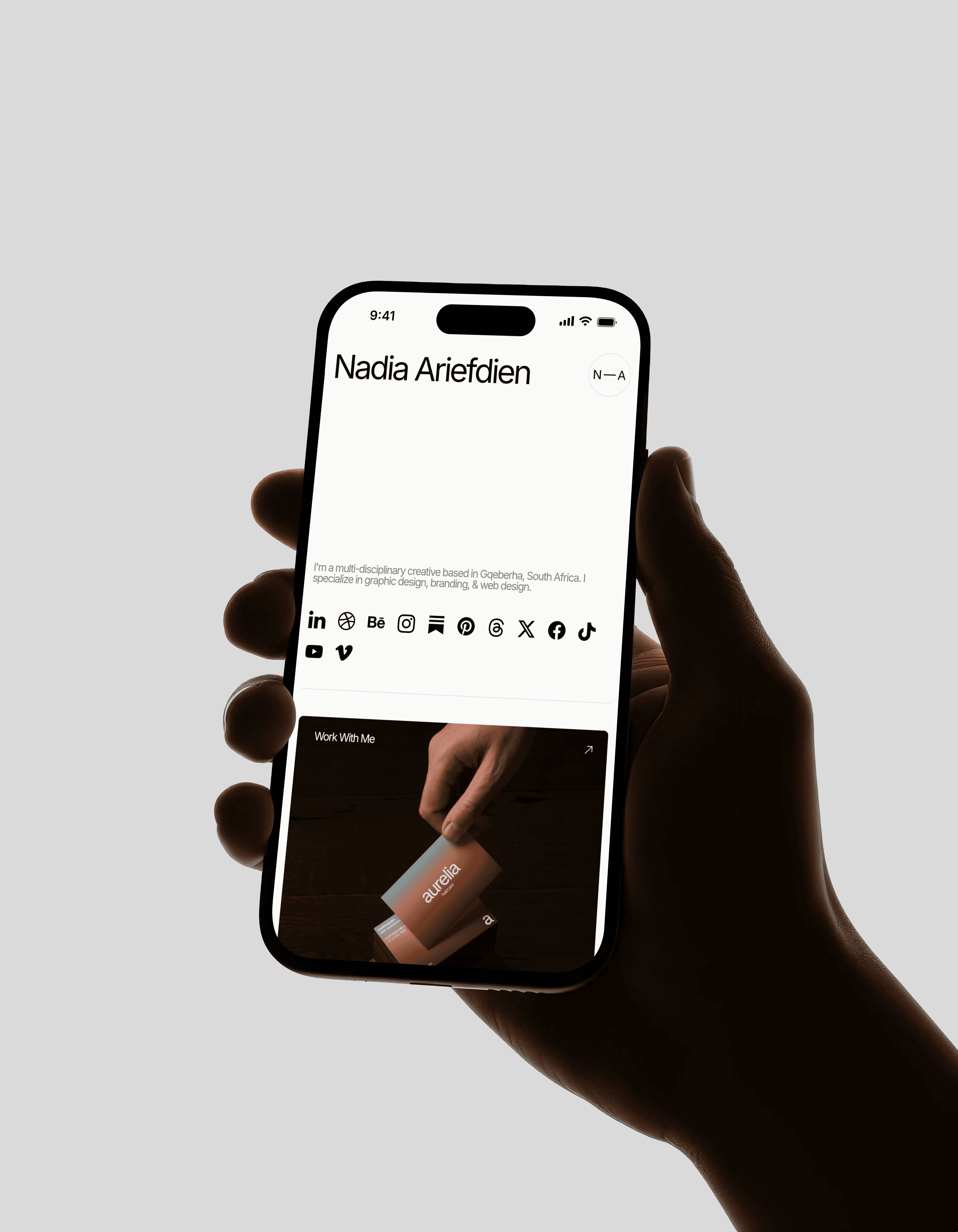 A person's hand holding an iPhone. The screen shows Nadia Ariefdien's link in bio website.