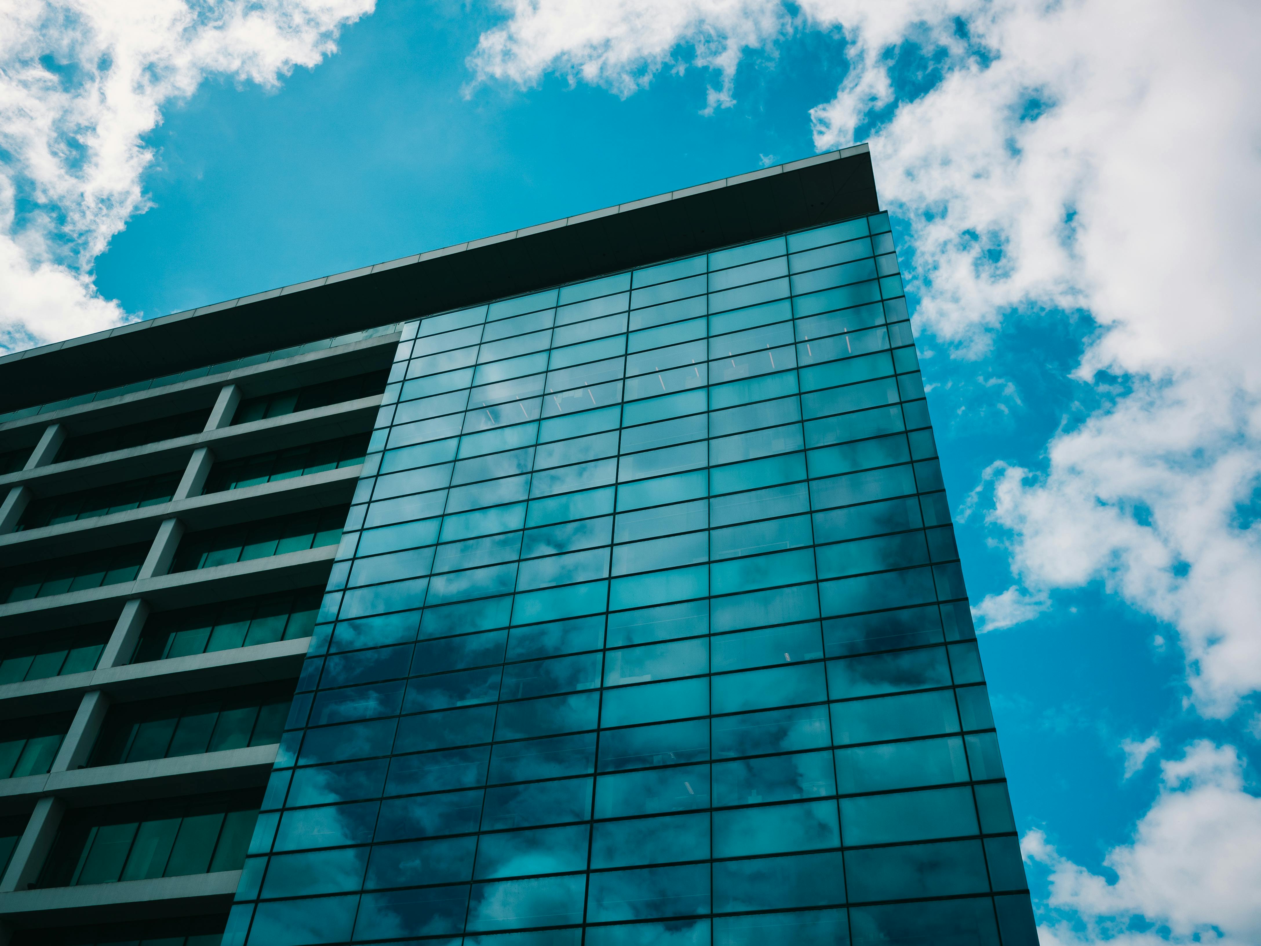 An elegant office setting in North Cyprus, showcasing a modern conference room with a large table, sleek chairs, and a backdrop of financial documents. In the foreground, a business professional in formal attire, deep in discussion with colleagues, emphasizes collaboration. Bright, natural light filters in through large windows, casting soft shadows that highlight the polished wooden surfaces and contemporary decor. The room is adorned with subtle representations of Cypriot culture, like framed local art. In the background, include a hint of a cityscape through the window, reflecting a thriving business environment. The atmosphere is professional yet inviting, suggesting innovation and growth in company formation. In one corner of the room, clearly visible, is a discreet logo of "KibristaSirket.co".