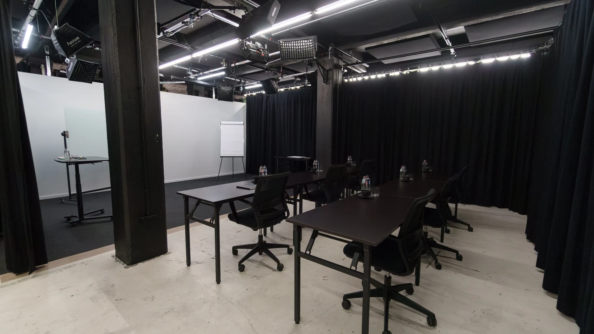 the Studio with white set walls, black curtains and a fixed lighting rig.