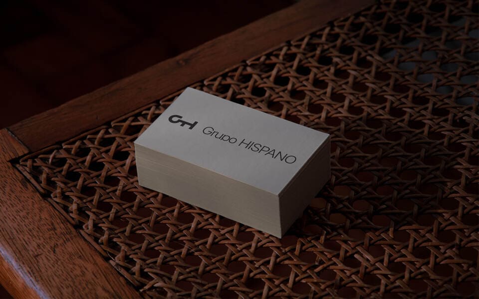 A photo of a small white box with the logo of Grupo Hispano, the box is standing on a wood chair.