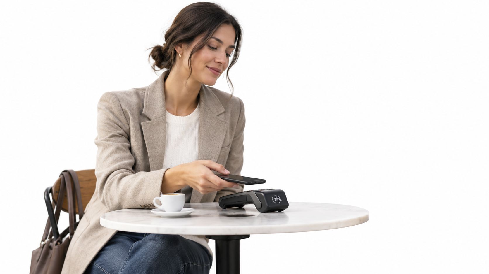 Una mujer joven pagando con su teléfono móvil en una terminal de pago inalámbrica en una cafetería.