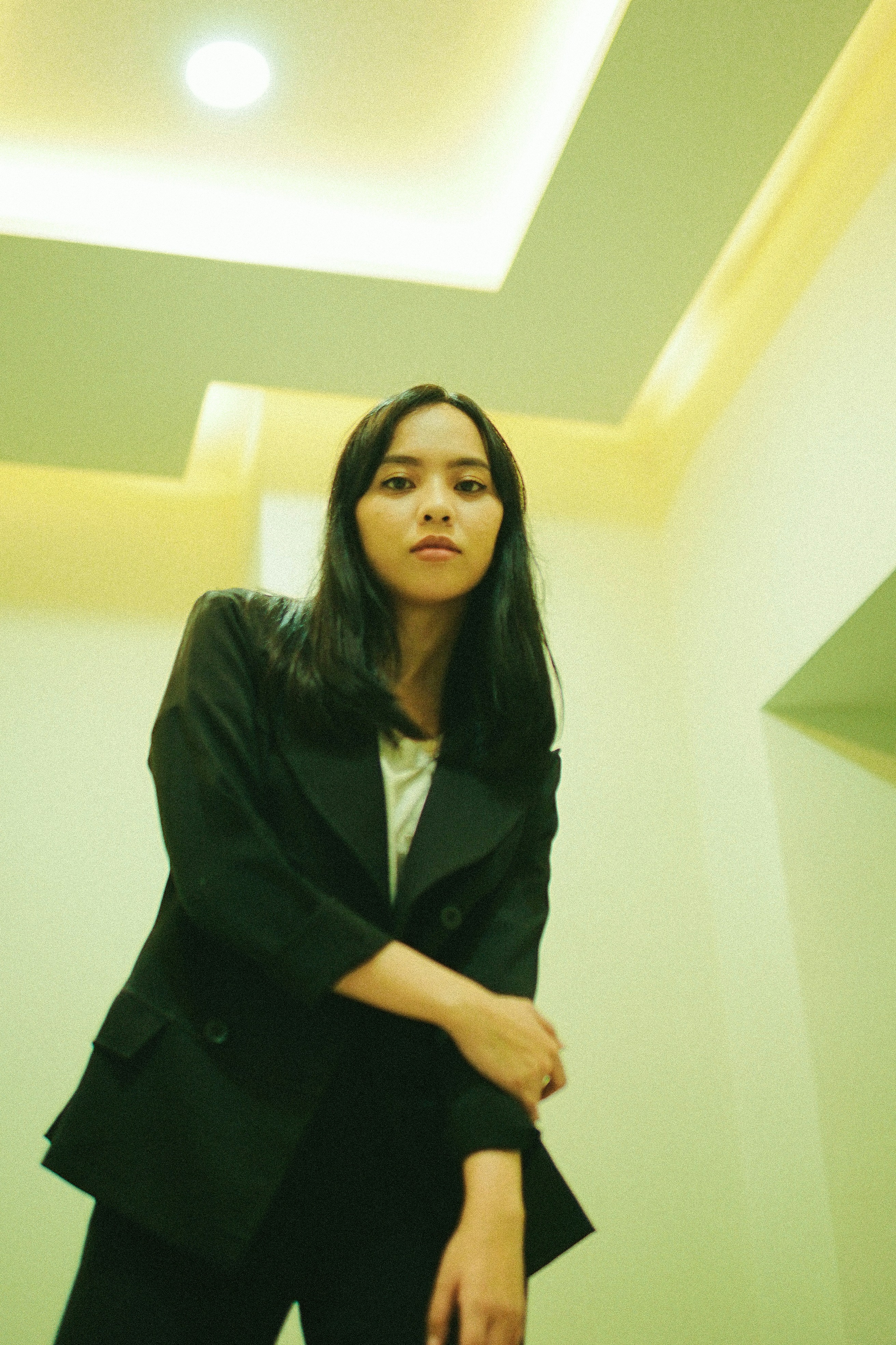 woman in black blazer standing near white wall