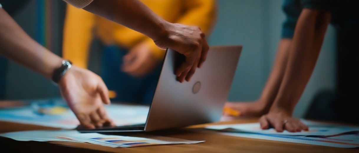 테이블 위 노트북과 자료를 두고 여러 사람이 함께 작업하는 협업 장면