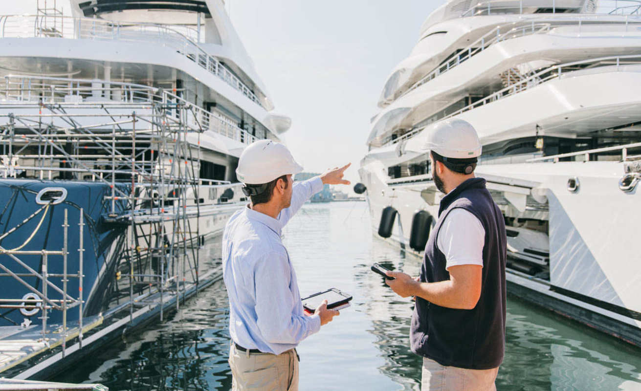 Dos profesionales revisando la construcción de un yate en astillero durante el proceso de compra