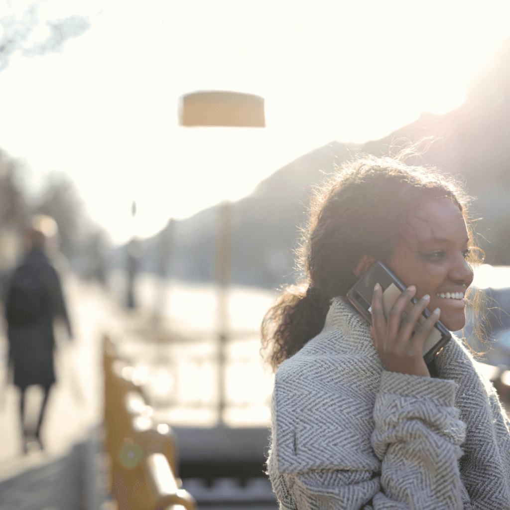 A woman talks on a cell phone, embodying affordable small business communication solutions with calling, texting, team phone numbers, and AI tasks management.