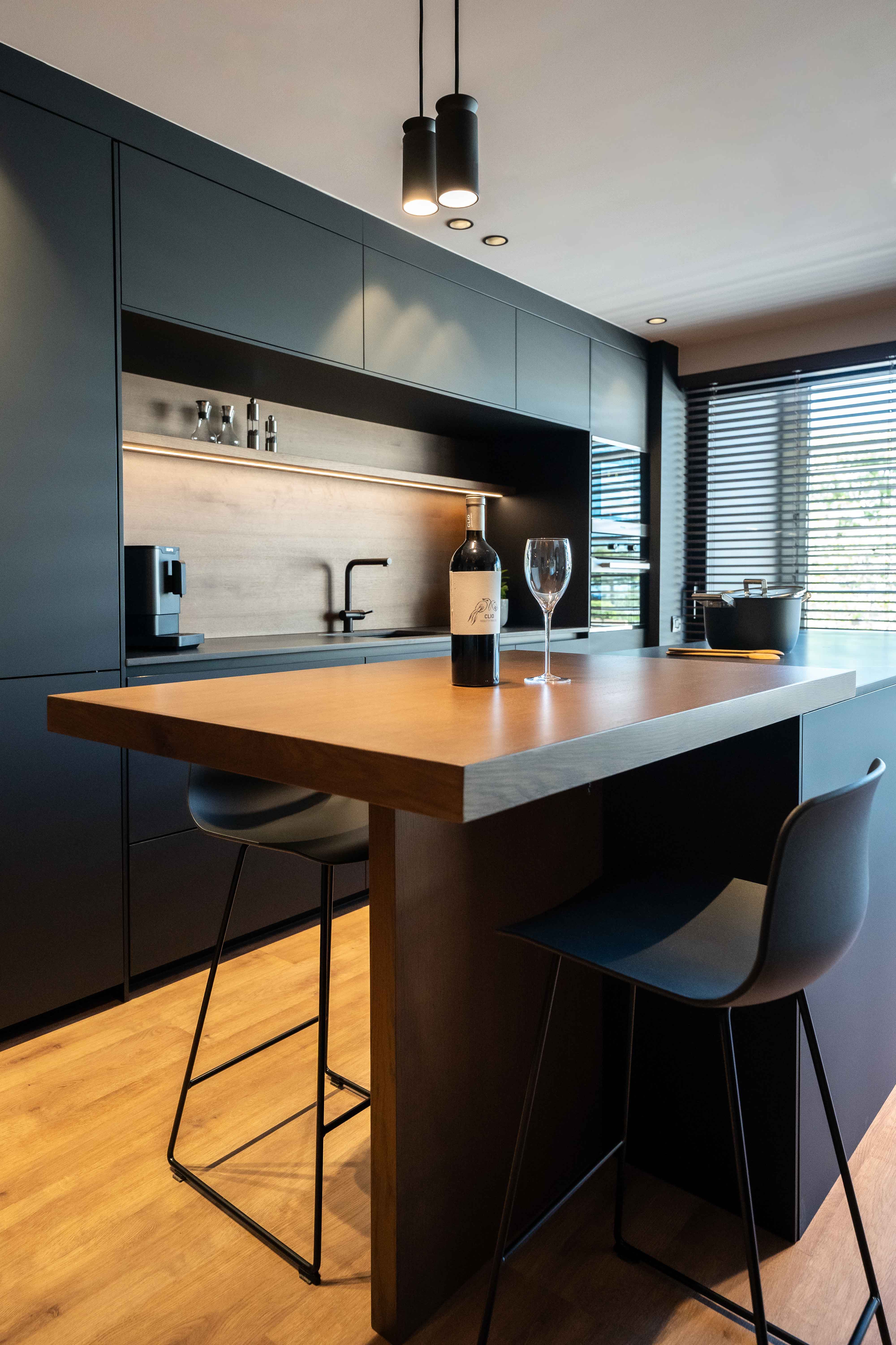 Cocina-comedor abierta de estilo oscuro con muebles y encimera de acabados negros