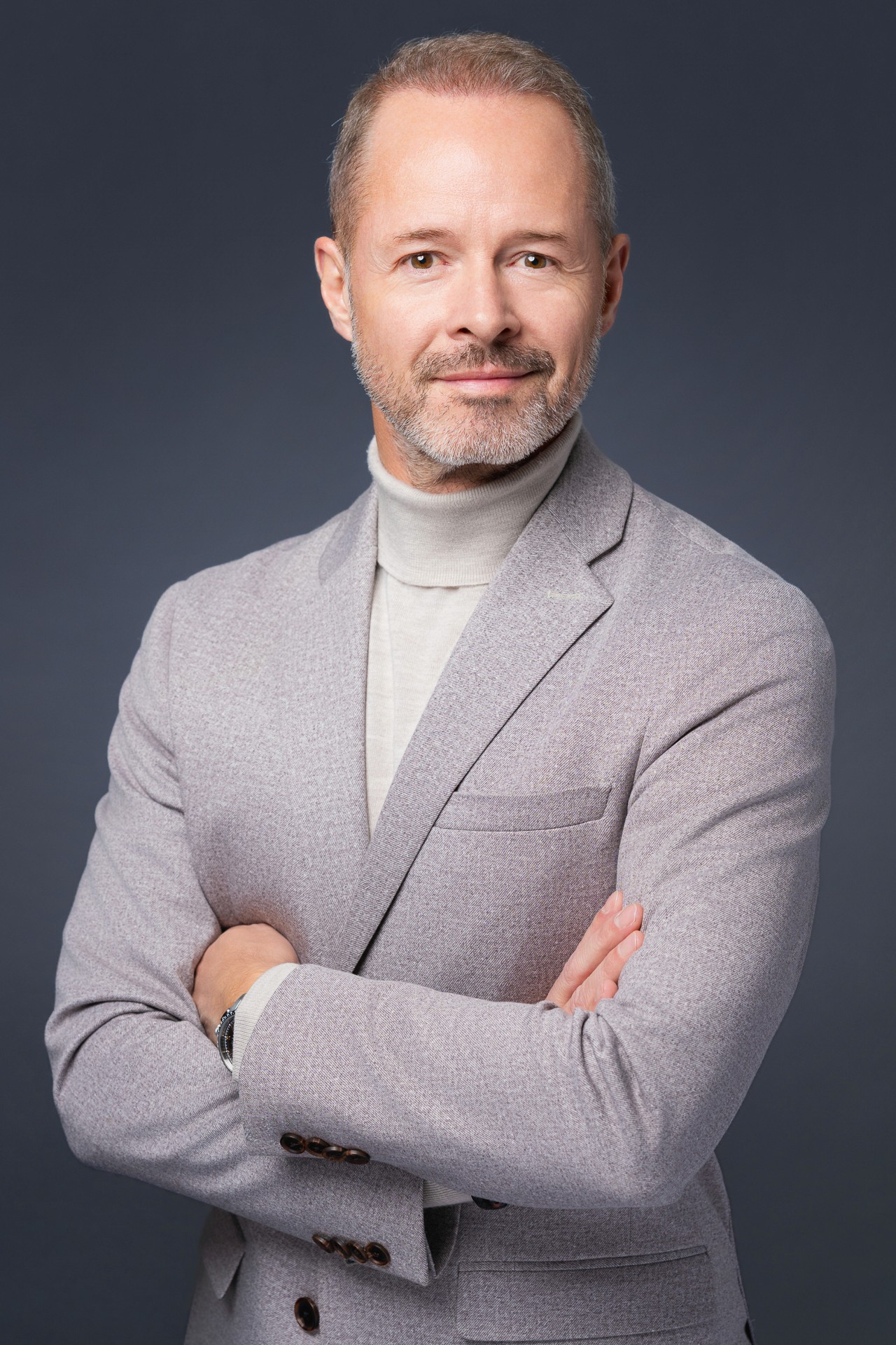 Modernes Business Portrait eines Mannes mit Rollkragenpullover in hellem Grau, aufgenommen im Fotostudio in Zürich