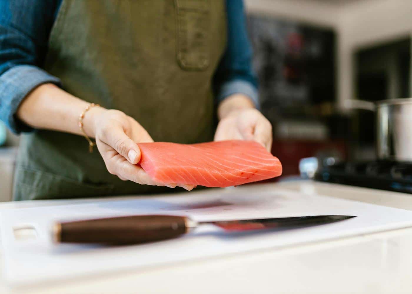 Person in kitchen holding fresh salmon
